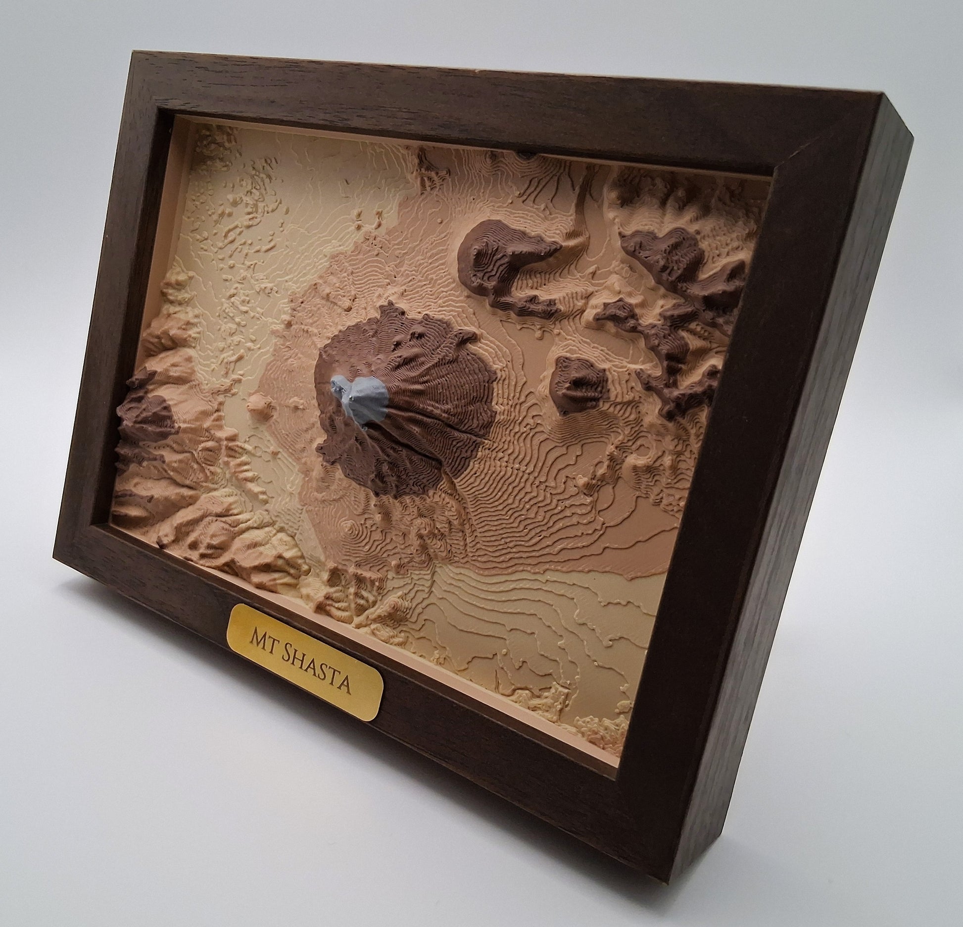 3D topographic model of Mount Shasta in a wooden frame on a white background