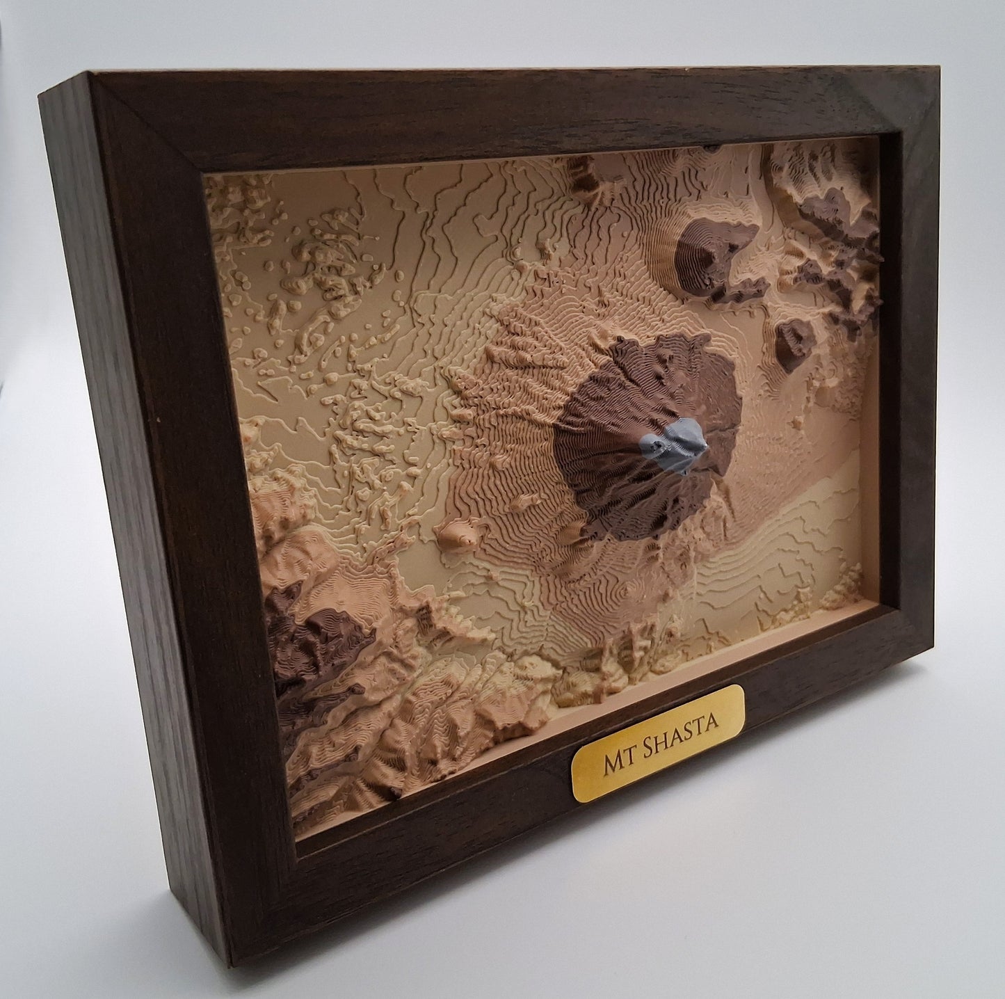 Topographic model of Mount Shasta in a wooden frame on a white background