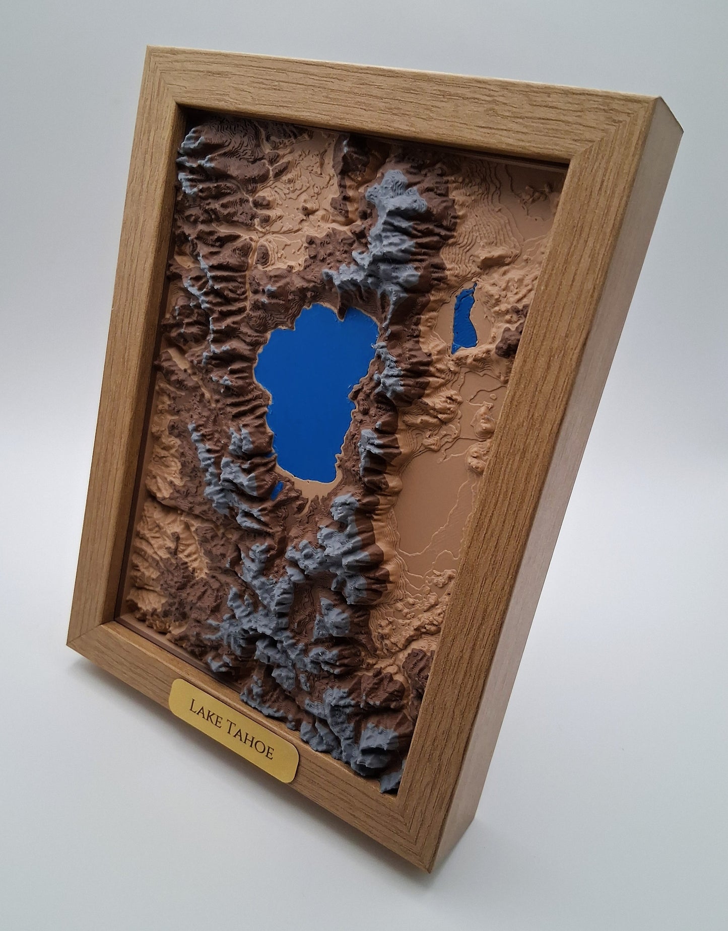 Topographic model of Lake Tahoe in a wooden frame on a white background