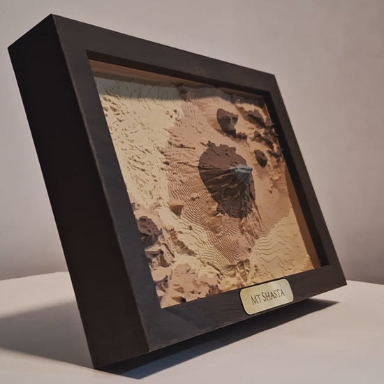 Topographic model of Mount Shasta in a wooden frame on a white background