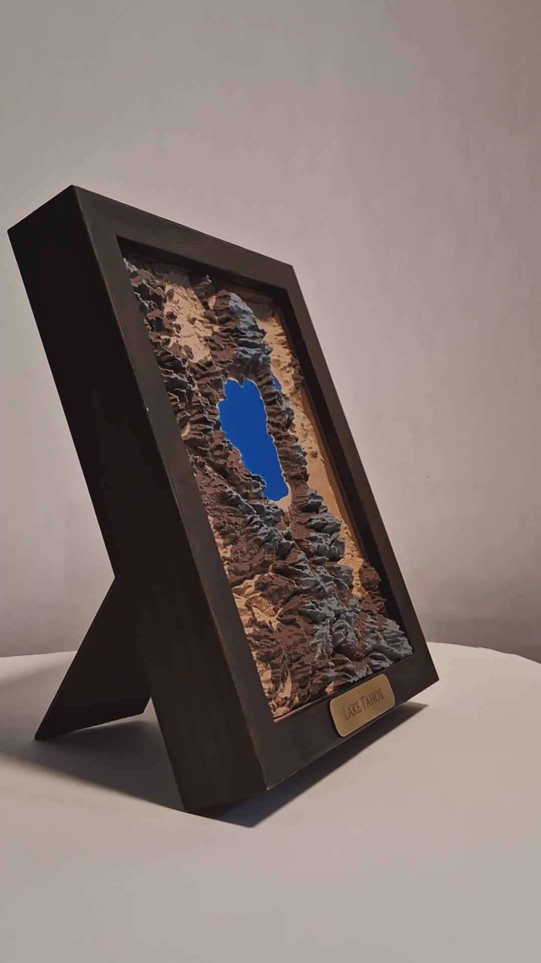 Topographic model of Lake Tahoe in a walnut frame on a light gray background